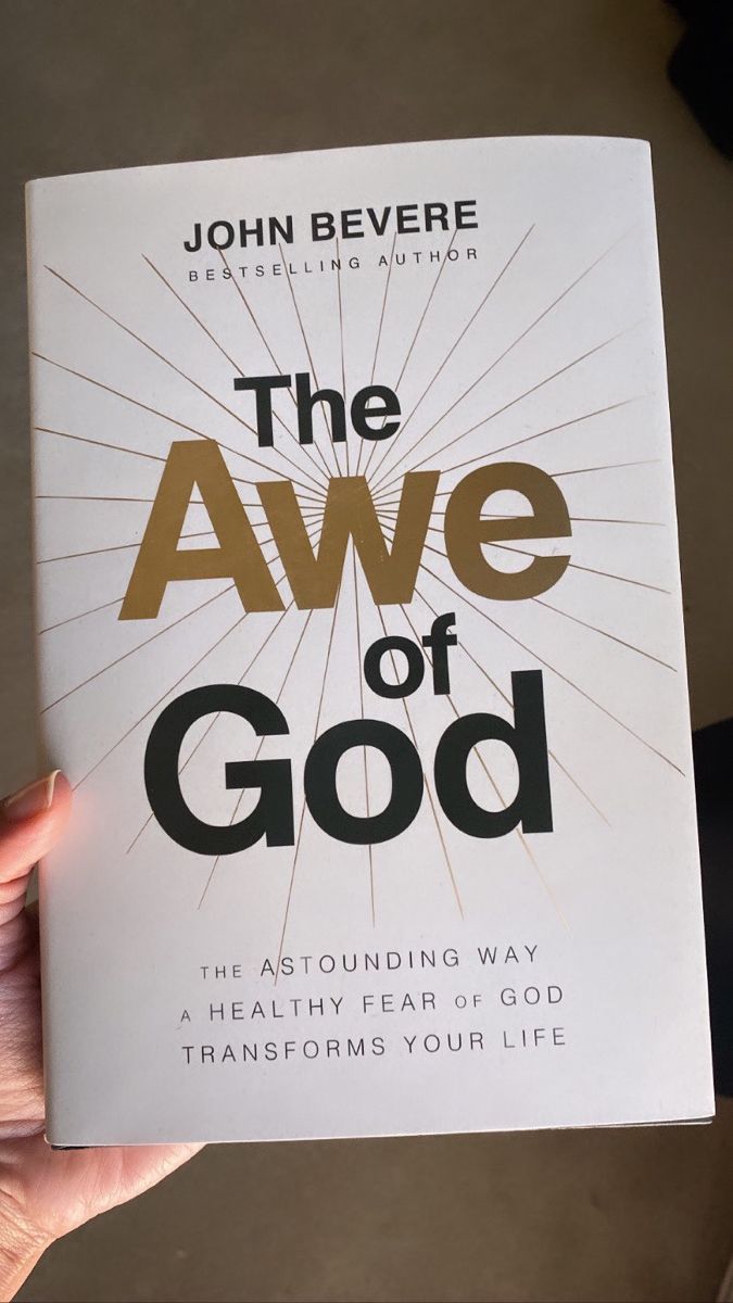 a person holding up a book about the awe of god