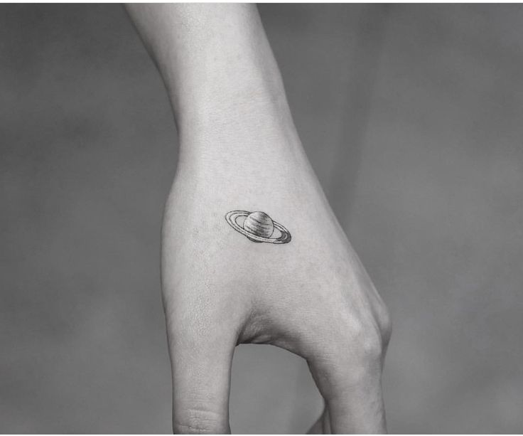 a hand with a saturn tattoo on it