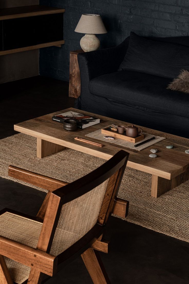 a wooden table sitting next to a couch in a living room on top of rugs