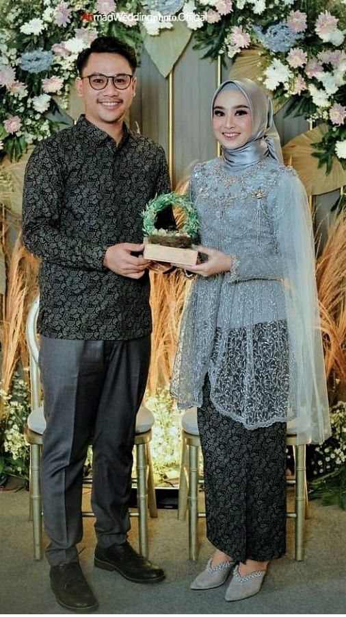 a man and woman standing next to each other in front of a floral display with flowers