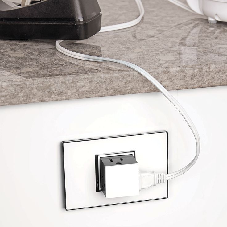 an electronic device plugged in to a wall charger on a counter with other electronics