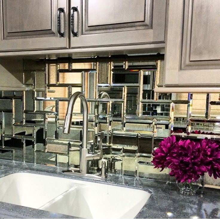 a kitchen counter with two sinks and some cabinets in the back ground, one has a vase of flowers on it