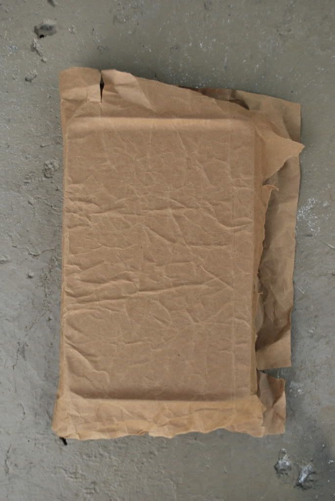 a piece of brown paper sitting on top of a cement floor next to a wall