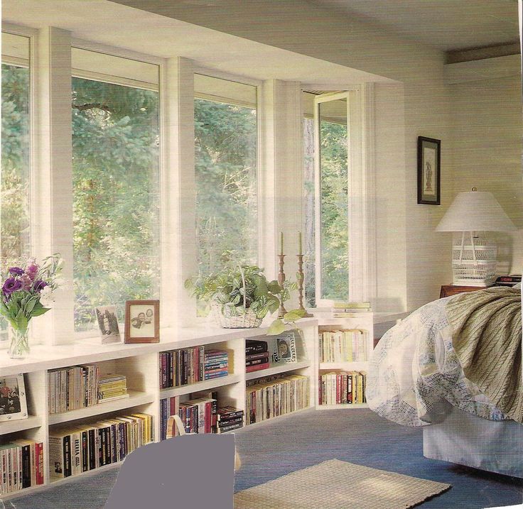 a bedroom with bookshelves filled with lots of books next to a bed and window