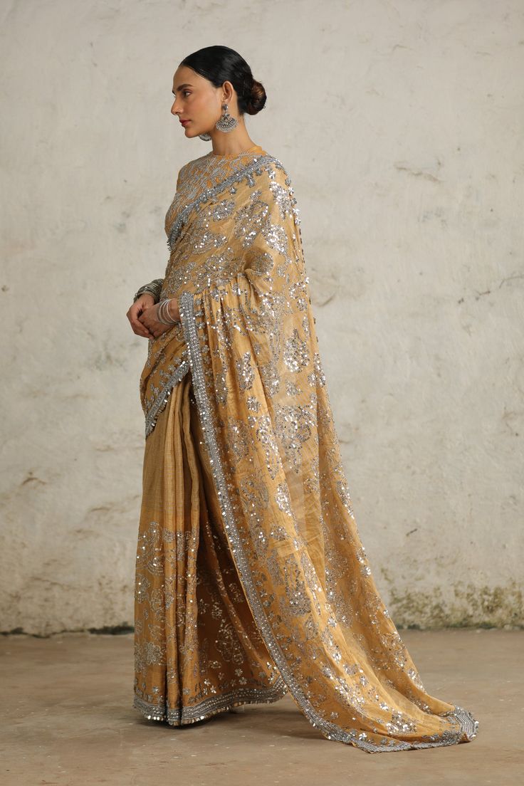 This sari is a tribute to the rich heritage of our country, featuring a luxurious handwoven 'Banarasi' tissue fabric delicately adorned with a stunning floral jaal crafted using metallic silver sequins. Each thread and stitch reflects the intricate craftsmanship of our artisans. Complete with an embroidered blouse, this ensemble is a timeless symbol of elegance and tradition, perfect for any special occasion. Festive Gold Embroidered Saree Fabric, Luxury Gold Embroidered Saree Fabric, Unstitched Gold Embroidered Saree Fabric, Unstitched Embroidered Gold Saree Fabric, Gold Embroidered Saree Fabric With Border, Silver Sequin, Embroidered Blouse, Indian Design, Metallic Silver