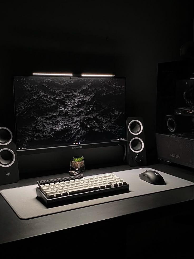 there is a computer monitor and keyboard on the desk in the dark room with speakers