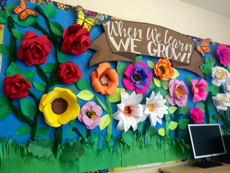 a classroom wall decorated with paper flowers and a sign that says when we learn we grow