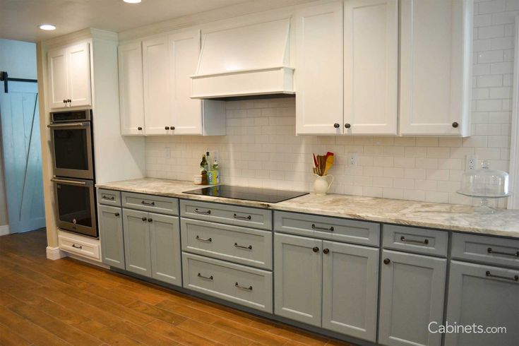 an empty kitchen with white cabinets and wood floors