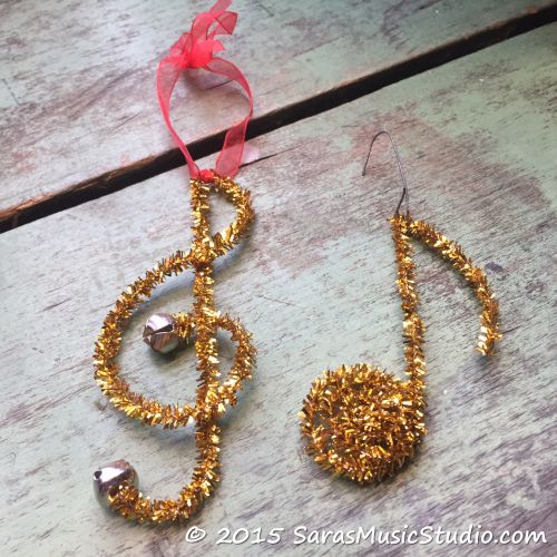 a musical note ornament made out of gold glitters and beads with a red ribbon