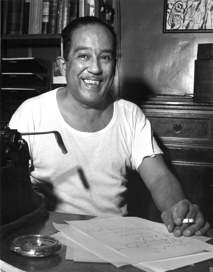 a black and white photo of a man sitting at a desk with papers in front of him