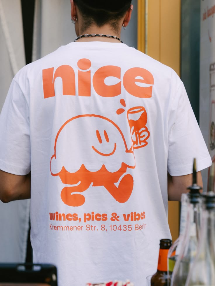 a man wearing an orange nice t - shirt standing in front of a counter