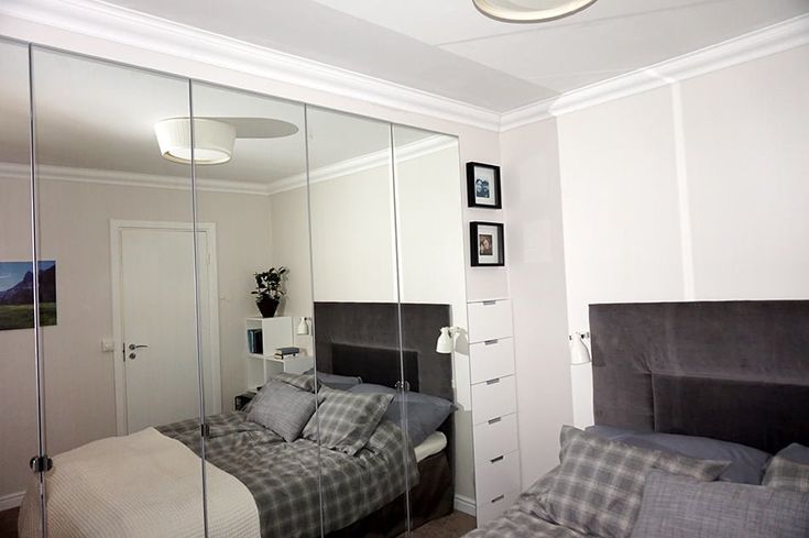 a bedroom with a bed, dresser and mirror in the corner that is reflecting it's image