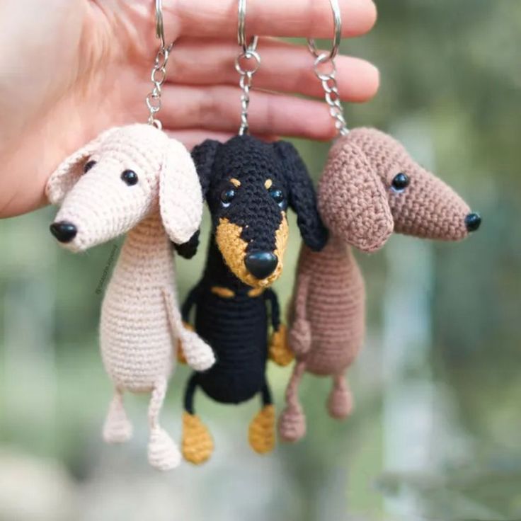 three crocheted dogs hanging from a person's hand