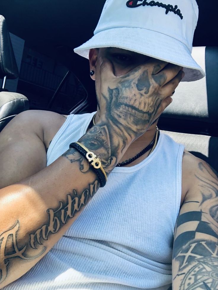 a man with tattoos on his face and arm sitting in the back seat of a car