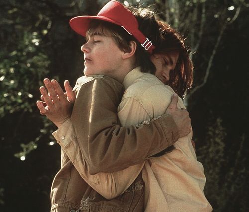 a boy and girl hugging each other in front of trees