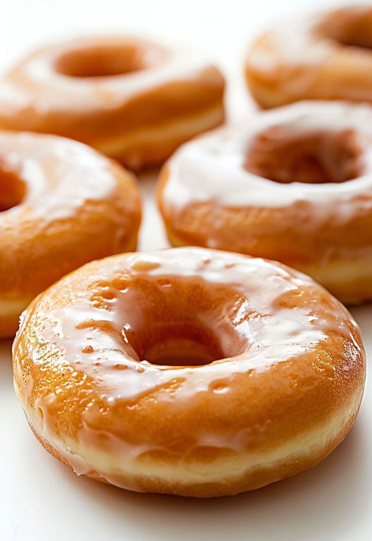 several glazed donuts on a white surface