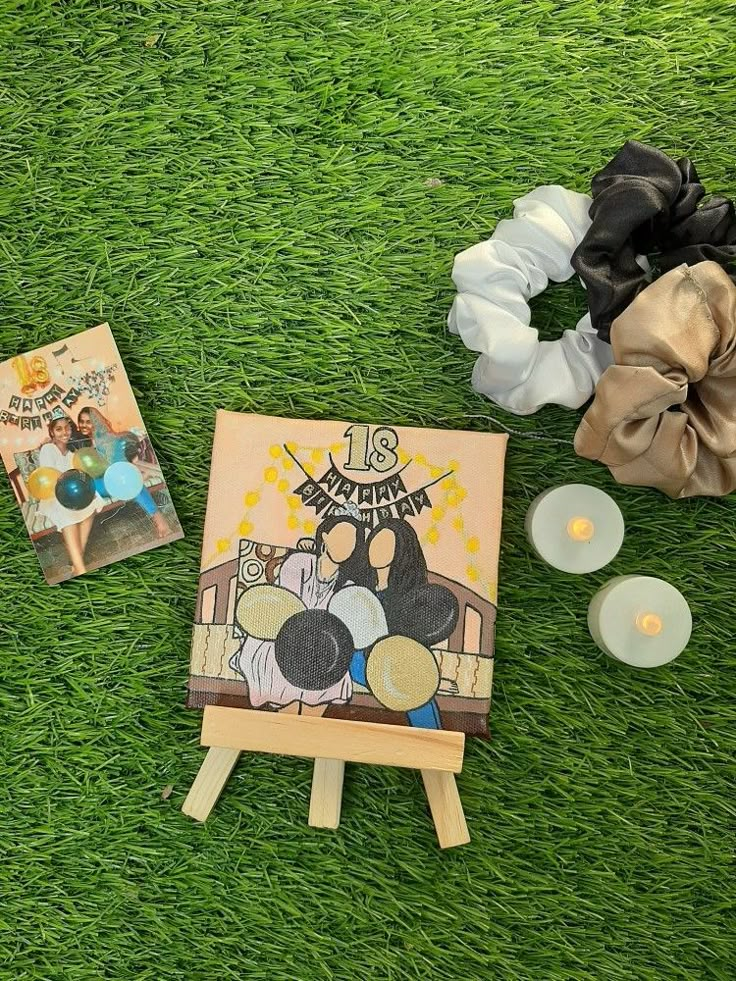 an easel with some pictures and candles on it sitting in the grass next to other items