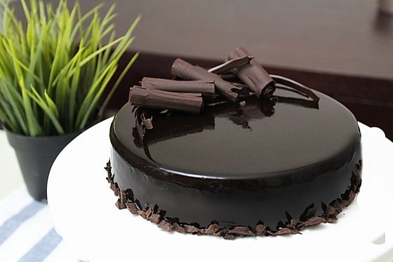 a chocolate cake sitting on top of a white plate next to a potted plant