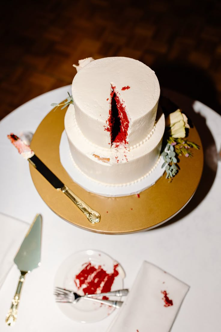 a white cake with blood on it sitting on top of a table next to silverware