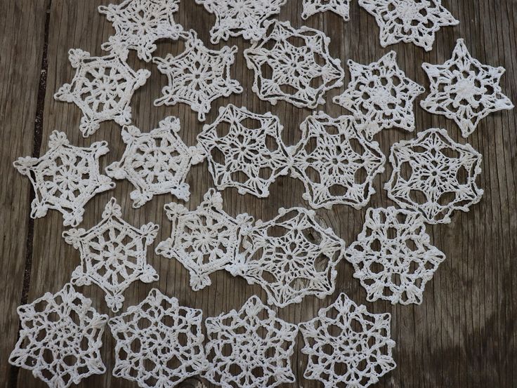 white crocheted snowflakes are laid out on a wooden table top