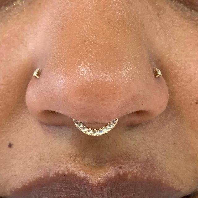 a close up of a person's nose with gold piercings on their nose