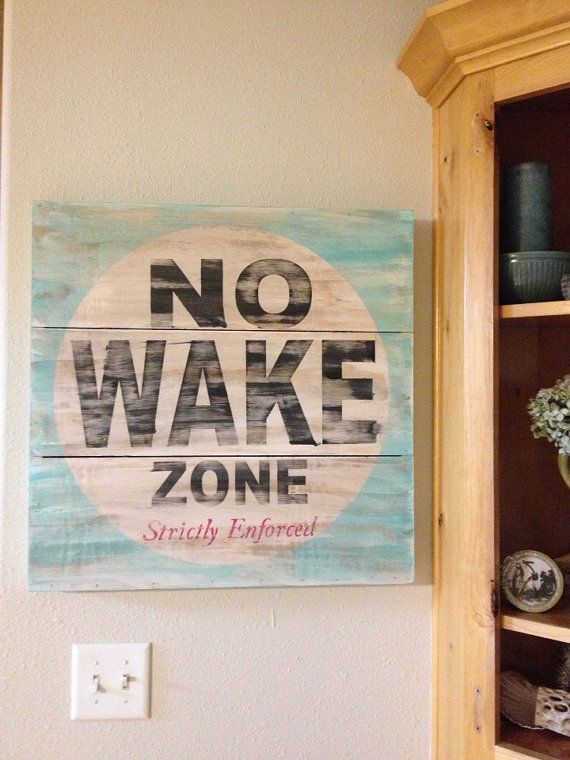 a wooden sign that says no wake zone on it next to a cabinet with vases