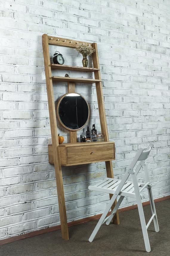 a wooden ladder leaning against a white brick wall with a mirror on it and two folding chairs