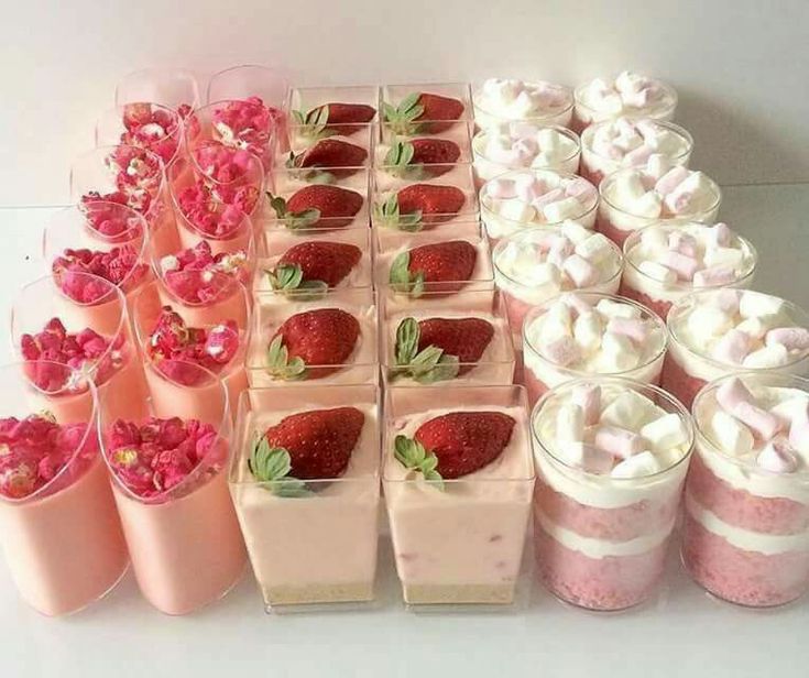 there are many desserts in cups on the table with strawberries and whipped cream