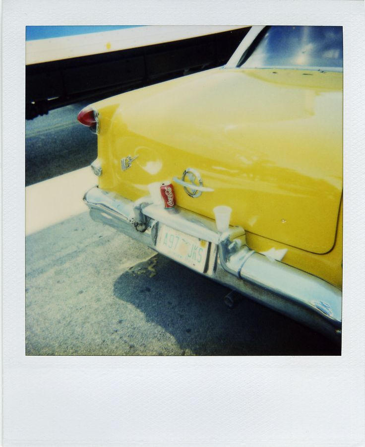 an old yellow car is parked on the street