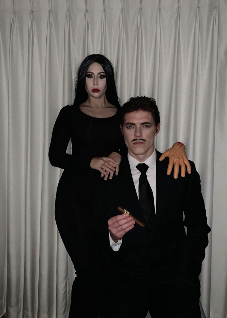 a man and woman dressed in black standing next to each other with fake hands on their chest