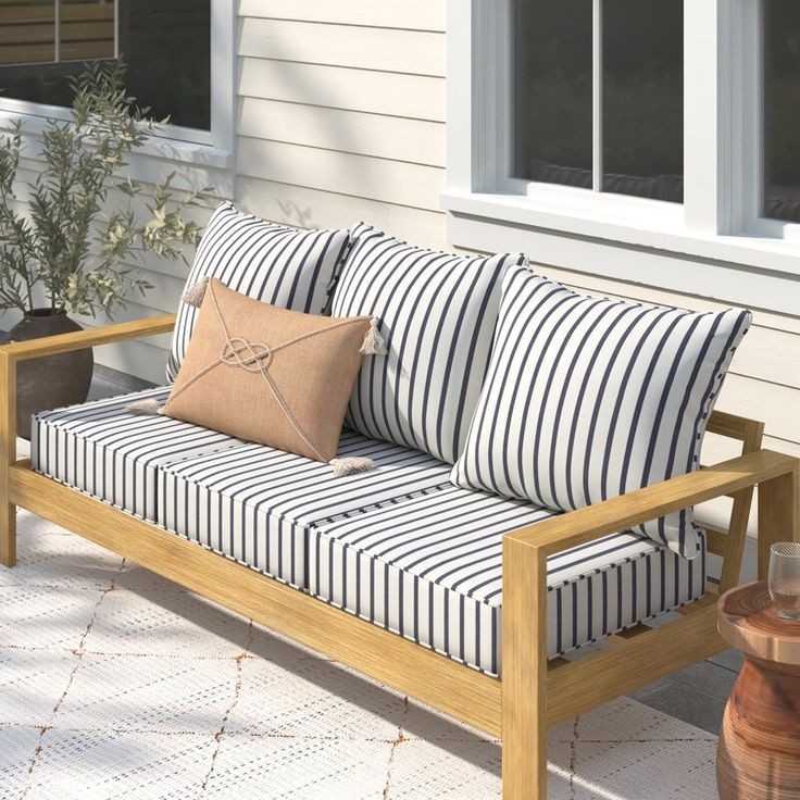 a wooden bench sitting on top of a patio next to a window and potted plant