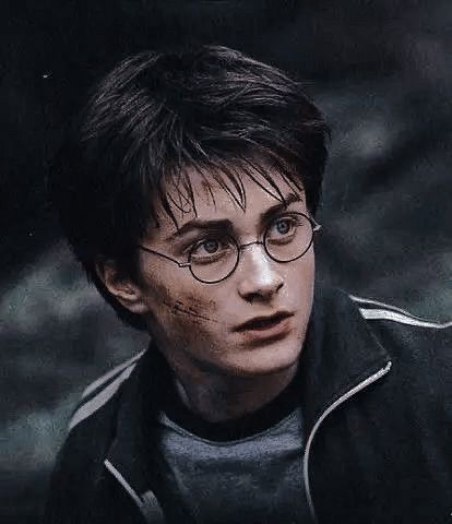 the young harry potter is wearing glasses and looking at something with blood on his face