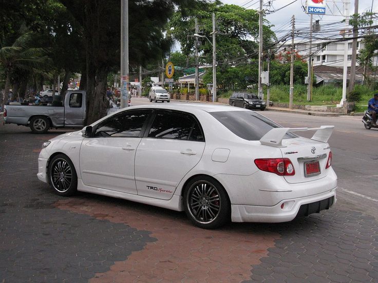 the white car is parked on the side of the road