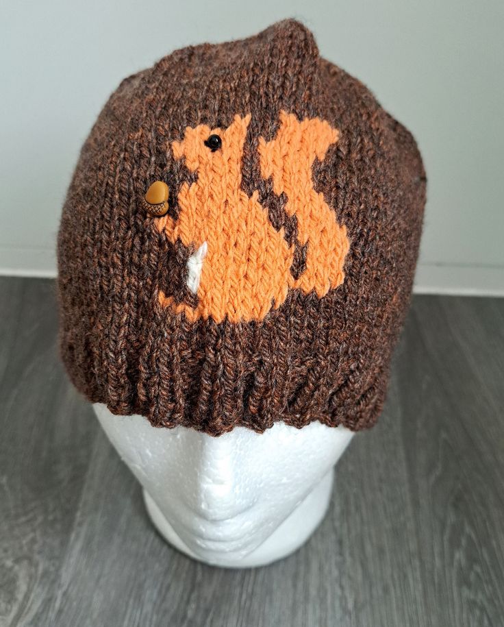 a knitted hat with an orange and brown squirrel design on it's brim