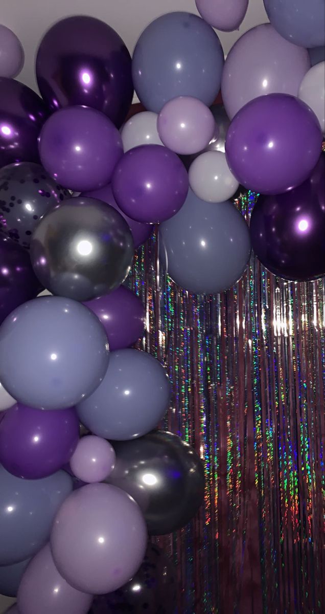 purple and silver balloons are hanging from the ceiling