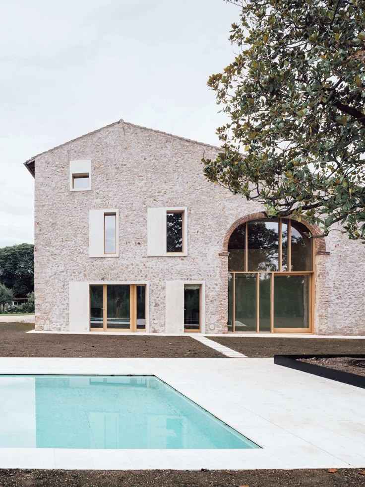 an empty swimming pool in front of a brick building with windows and doors on the side