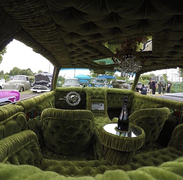 the interior of an old car with green velvet upholstered seats and round tables