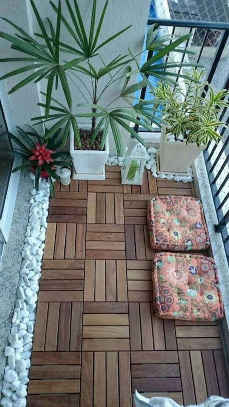 a small balcony with potted plants on the floor and two chairs next to it