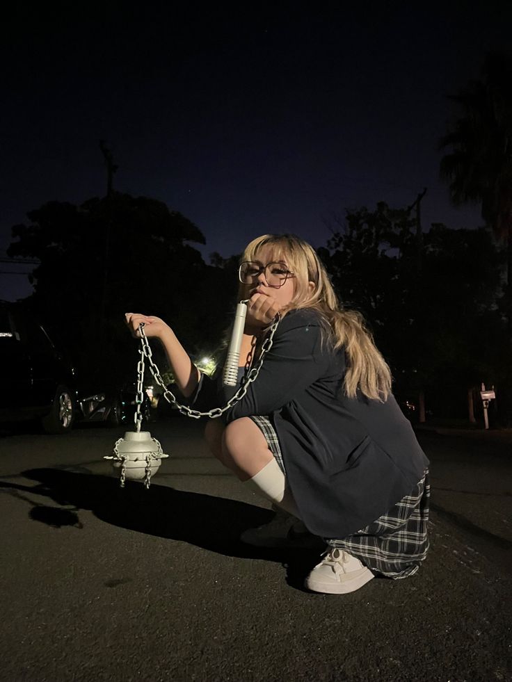 a woman kneeling down next to a white fire hydrant in the street at night