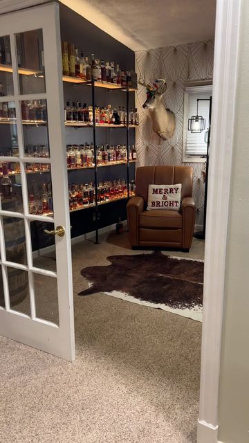 a living room filled with furniture and shelves full of bottles on the wall next to an open door