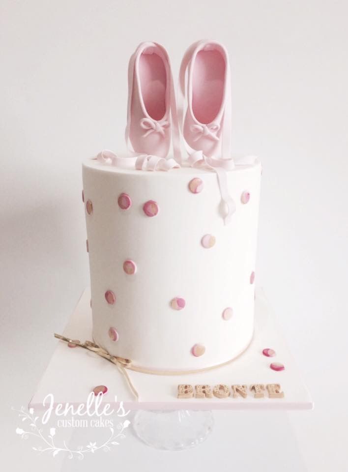 a white cake with pink shoes on top and confetti sprinkles