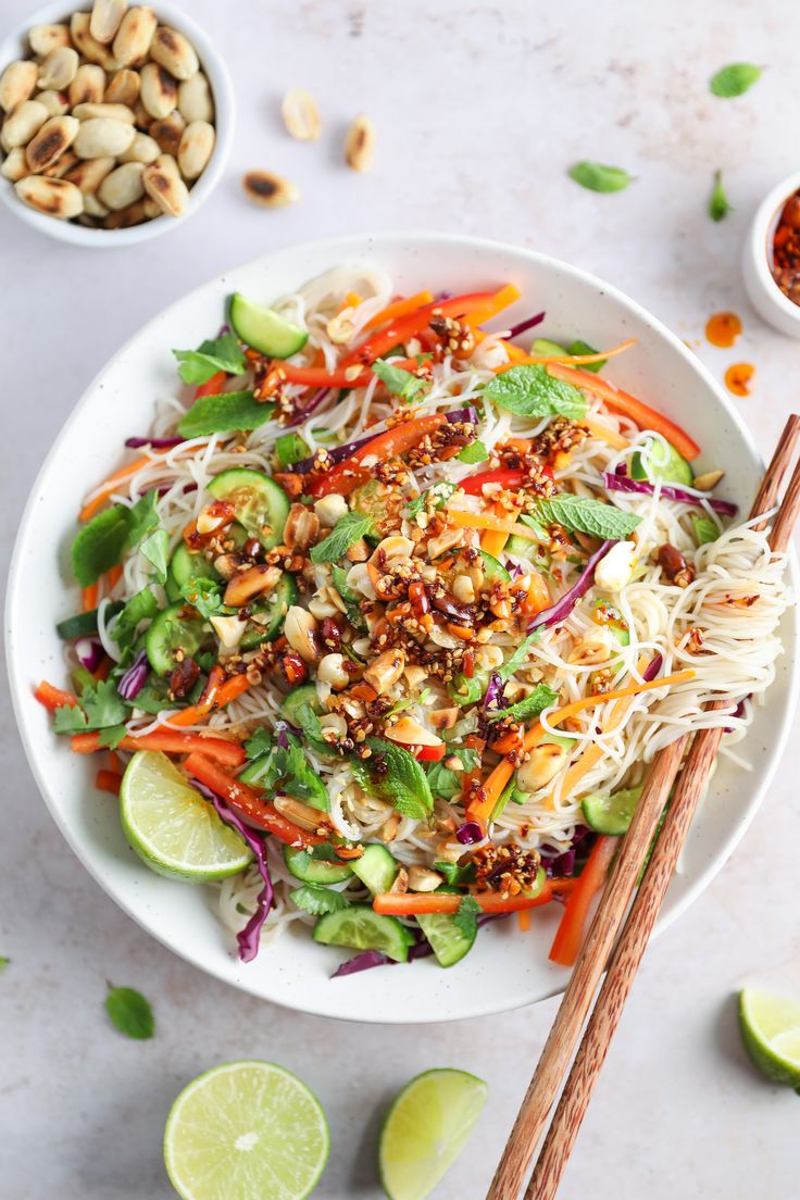 a white bowl filled with salad and chopsticks on top of a marble table