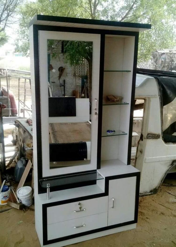 a white and black cabinet sitting in the dirt