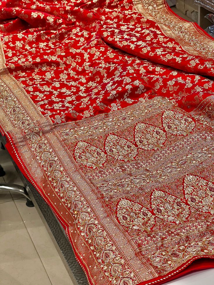 Crafted with stunning red Banarasi silk, this saree features an intricate Jaal pattern and is embellished with red and golden Zardosi, hand embroidery, moti, cuddana, and gotapatti. Exuding elegance and sophistication, this saree is perfect for any special occasion. Experience luxury and style with this Red Banarasi Silk Jaal Zardosi Hand Embroidery Saree. Luxury Red Banarasi Silk Traditional Wear, Luxury Dola Silk Saree With Dabka Work, Luxury Red Brocade Saree, Luxury Red Banarasi Silk Dupatta, Luxury Resham Embroidery Banarasi Silk Dupatta, Luxury Banarasi Silk Shawl With Zari Work, Luxury Banarasi Silk Shawl With Cutdana, Luxury Banarasi Silk Dupatta With Resham Embroidery, Luxury Red Banarasi Silk Embroidered Fabric