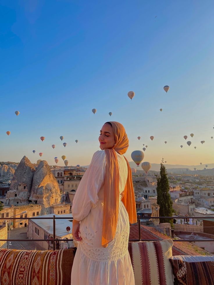 a woman standing on top of a roof next to hot air balloons