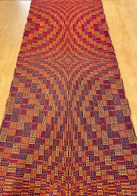 an orange and red rug sitting on top of a wooden floor