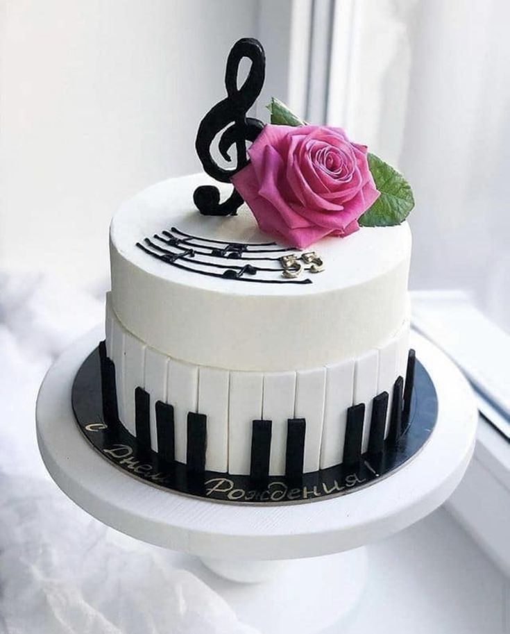 a cake decorated with music notes and a pink rose