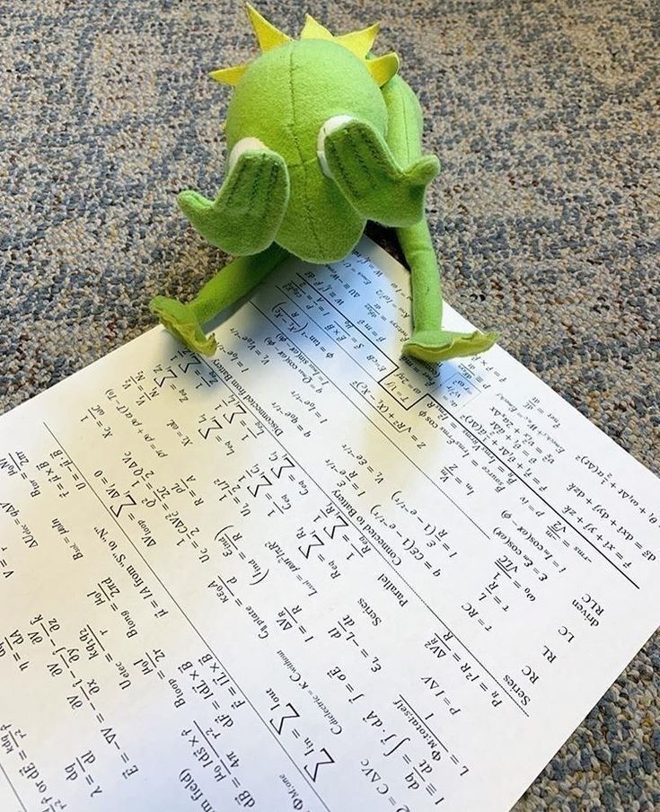 a green stuffed animal sitting on top of a piece of paper with numbers written in it