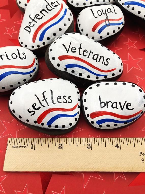 some rocks with words painted on them next to a measuring tape and red white and blue stars