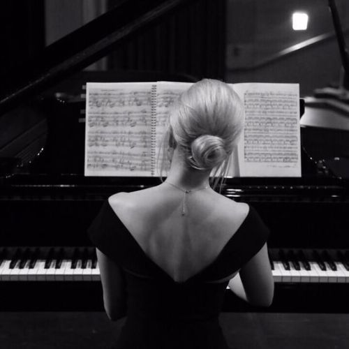 a woman sitting in front of a piano with sheet music on it's back